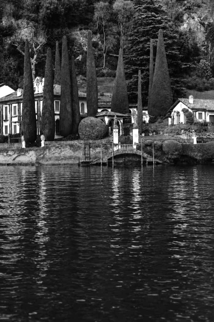 Historic lakeside villa with cypress trees overlooking Lake Como in Italy.