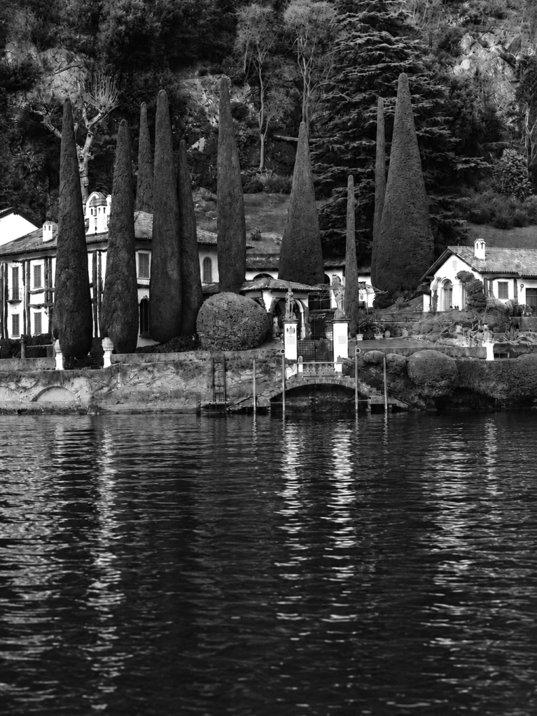 Historic lakeside villa with cypress trees overlooking Lake Como in Italy.