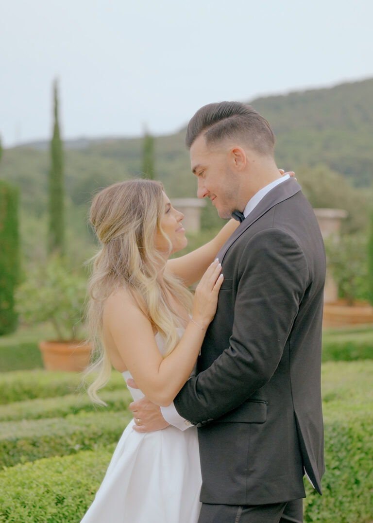 Destination Wedding Videographer Italy 4 Luxury destination wedding couple embracing in an elegant Italian villa garden surrounded by cinematic landscapes.