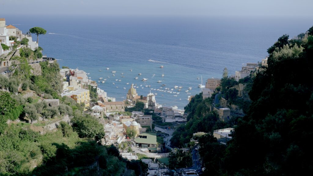 Panoramic view of Positano on the Amalfi Coast with sea, boats, hillside houses and the Church of Santa Maria Assunta.