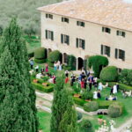 Why U.S. Couples Choose Italian Wedding Videographers 1 Aerial view of a luxury wedding reception at a historic Tuscan villa surrounded by cypress trees and gardens in Italy.