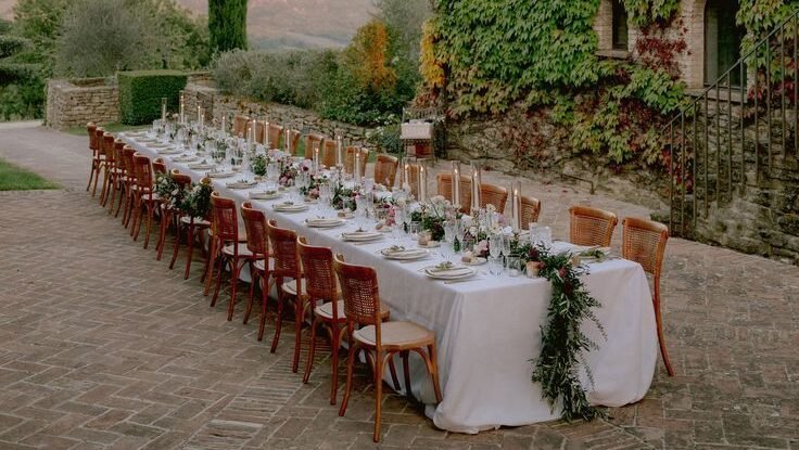 Luxury outdoor wedding reception in Umbria, Italy, with long imperial table, string lights, and ivy-covered historic villa.