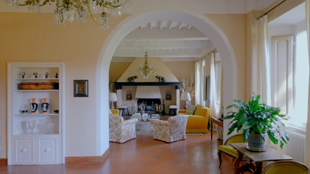 Luxury interior living room at La Pescaia Resort featuring chandeliers, fireplace and classic Tuscan design.