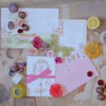 Luxury wedding invitation flat lay with floral stationery, colorful fruit, vintage artwork and elegant Italian wedding details.