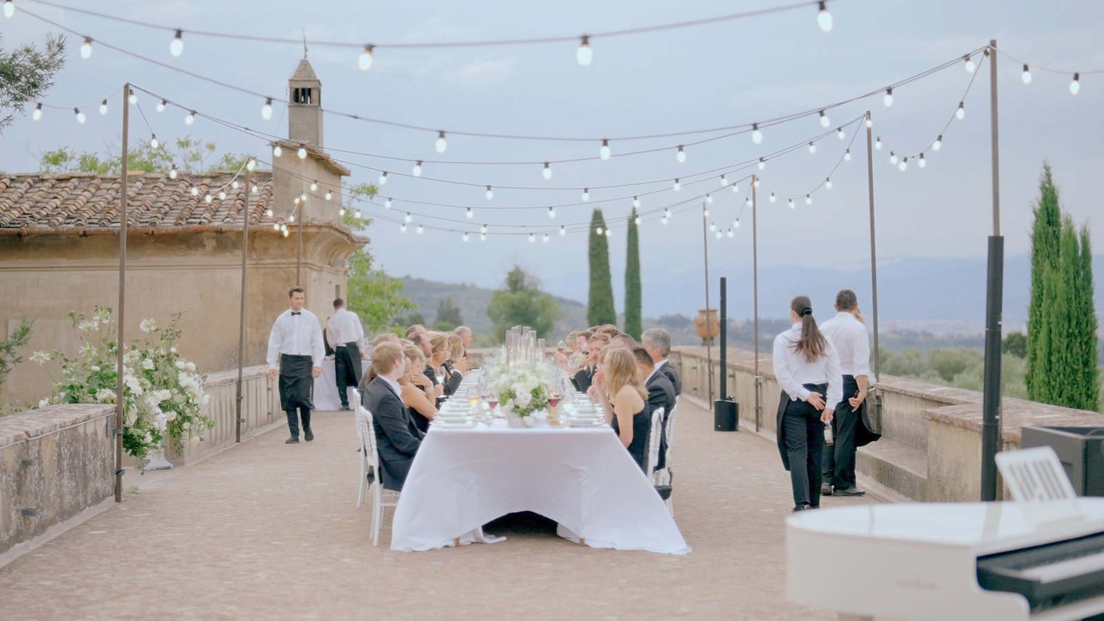 Wedding Videographer Florence in Italy 4 Outdoor wedding reception on terrace at Villa Medicea di Lilliano Florence — long table under string lights with Tuscan hills in background, luxury wedding film by Giancarlo De Vita