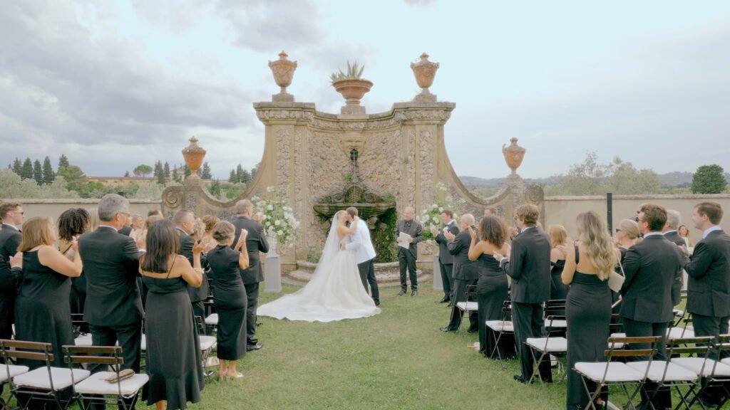 Wedding Videographer Florence in Italy 3 Outdoor wedding ceremony at Villa Medicea di Lilliano Florence — bride and groom first kiss in front of a baroque stone fountain, luxury wedding film by Giancarlo De Vita
