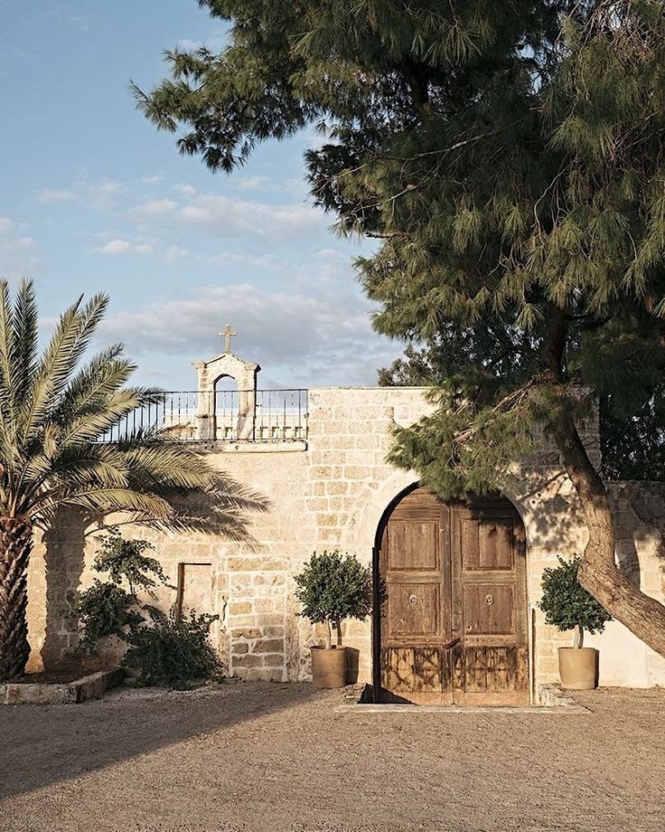 Italy Wedding videographer 3 Puglia masseria wedding venue stone entrance with arched wooden doors at golden hour