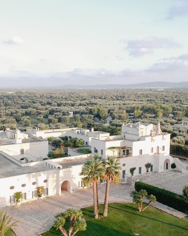 Wedding Videographer Puglia 4 Aerial view of a whitewashed Puglia masseria resort surrounded by olive groves at sunset