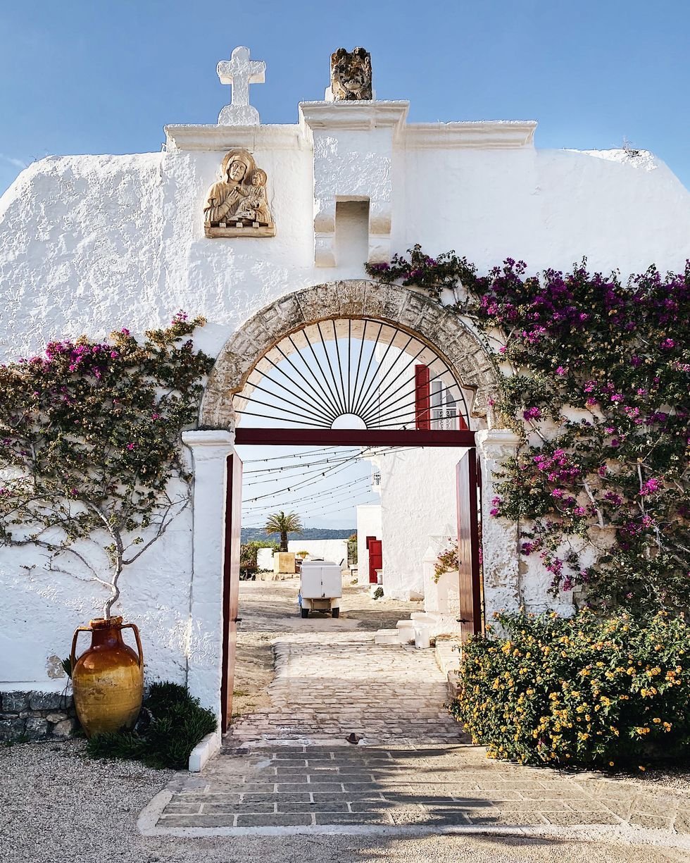 Wedding Videographer Puglia 3 Whitewashed arched entrance with bougainvillea and chapel niche at a Puglia masseria wedding venue